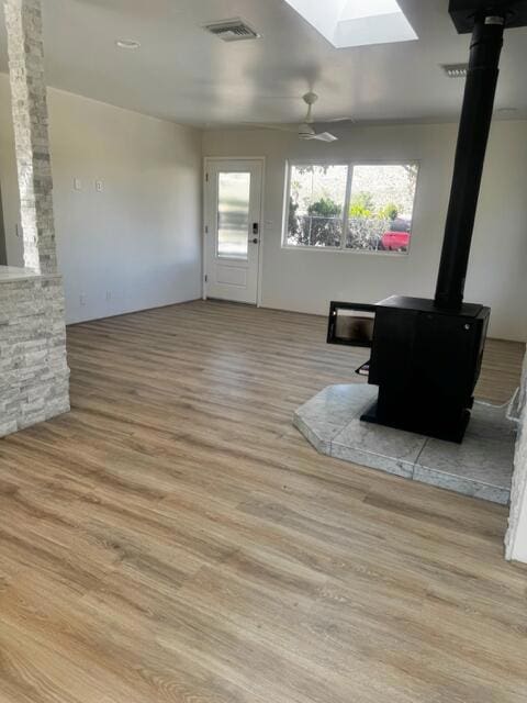 living room featuring ceiling fan, a skylight, and light hardwood / wood-style flooring