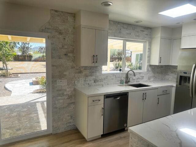 kitchen with stainless steel appliances, sink, light wood-type flooring, and white cabinets