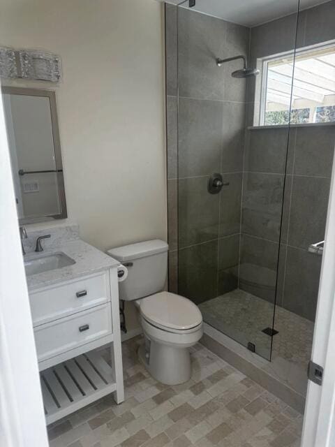 bathroom with toilet, vanity, and a shower with door