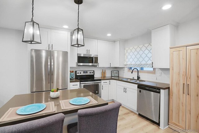 kitchen with a center island, sink, light hardwood / wood-style flooring, decorative light fixtures, and stainless steel appliances