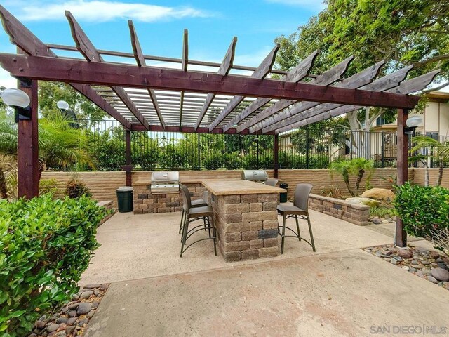 view of patio / terrace featuring an outdoor kitchen, a pergola, exterior bar, and grilling area