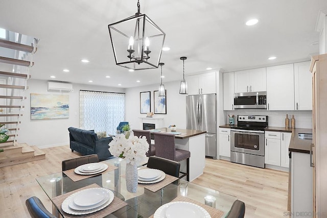 dining area featuring an inviting chandelier, light hardwood / wood-style flooring, a wall mounted AC, and sink