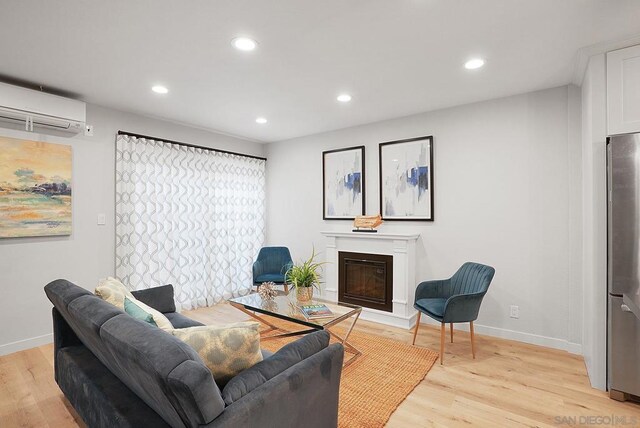 living room featuring light wood-type flooring and a wall unit AC