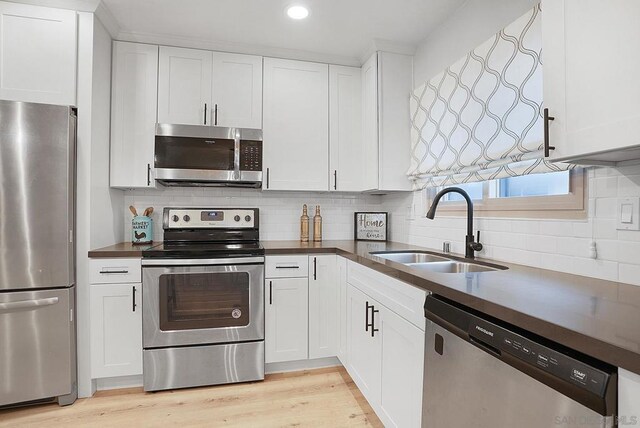 kitchen with stainless steel appliances, white cabinetry, light hardwood / wood-style floors, and sink