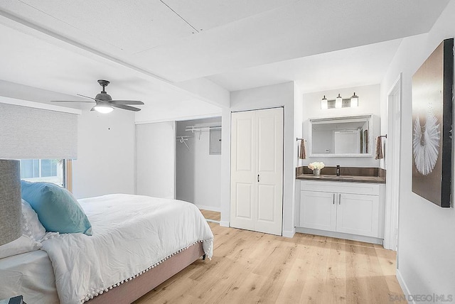 bedroom with light hardwood / wood-style flooring, ceiling fan, and sink