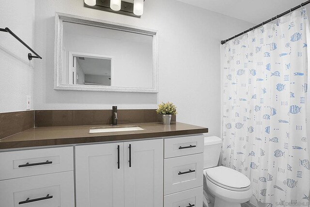 bathroom featuring curtained shower, vanity, and toilet