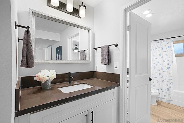 full bathroom with toilet, hardwood / wood-style floors, vanity, and shower / tub combo with curtain