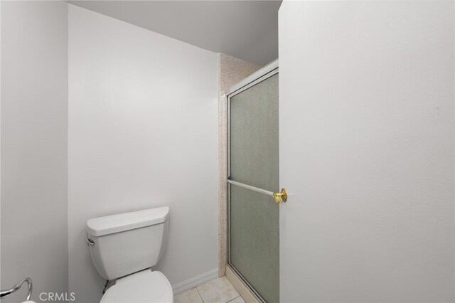 bathroom with a shower with shower door, toilet, and tile patterned flooring