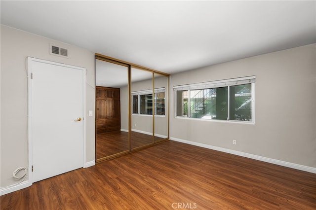 unfurnished bedroom with a closet and dark hardwood / wood-style flooring