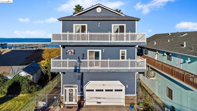 back of house with a garage, a water view, and a balcony