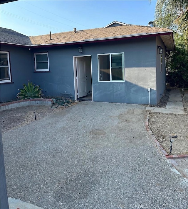 view of front facade with a patio area and roof with shingles