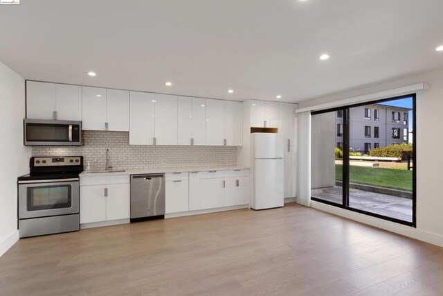 kitchen featuring tasteful backsplash, sink, light hardwood / wood-style flooring, stainless steel appliances, and white cabinets