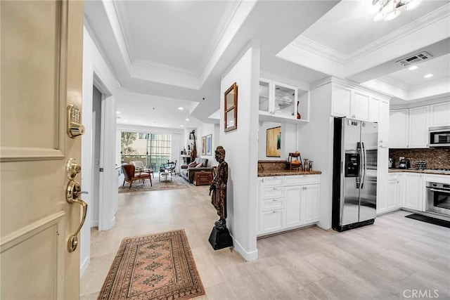 kitchen with a raised ceiling, white cabinets, dark stone counters, and appliances with stainless steel finishes