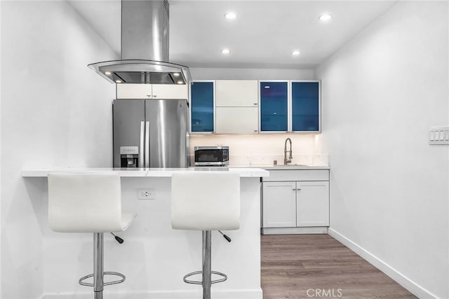 kitchen with sink, white cabinetry, a kitchen breakfast bar, light hardwood / wood-style flooring, and appliances with stainless steel finishes