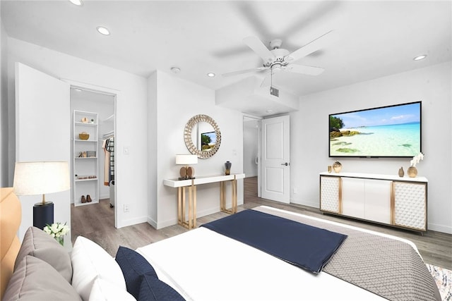 bedroom featuring ceiling fan, light hardwood / wood-style flooring, a closet, and a spacious closet