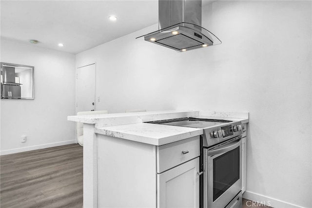 kitchen with kitchen peninsula, island range hood, white cabinetry, hardwood / wood-style flooring, and stainless steel electric stove