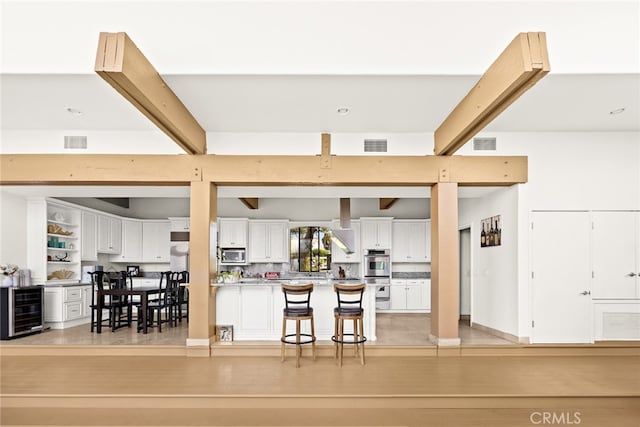 interior space with white cabinetry, wine cooler, a breakfast bar, stainless steel appliances, and light hardwood / wood-style flooring