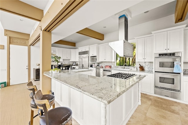 kitchen with ventilation hood, built in appliances, white cabinetry, and light stone countertops