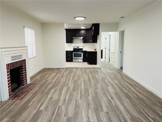 unfurnished living room with light hardwood / wood-style flooring and a brick fireplace