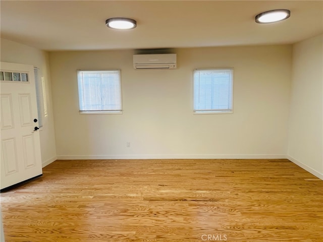 unfurnished room with light hardwood / wood-style floors and a wall unit AC