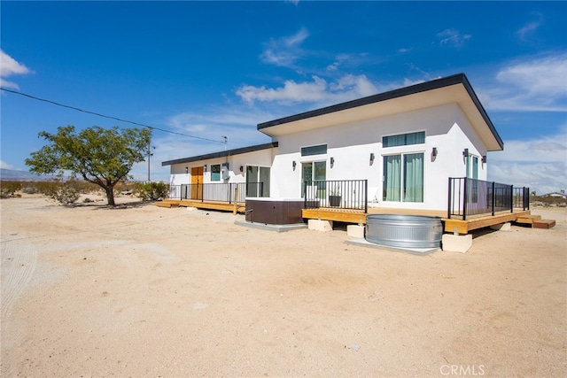 rear view of property with a hot tub and a deck