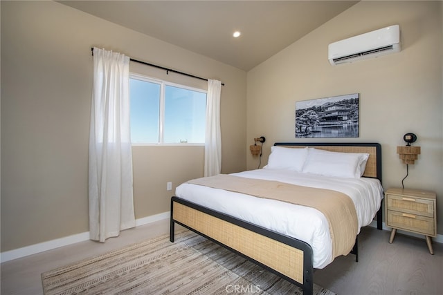 bedroom featuring light hardwood / wood-style floors, vaulted ceiling, and a wall unit AC