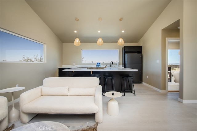 living room featuring lofted ceiling, light hardwood / wood-style floors, and sink