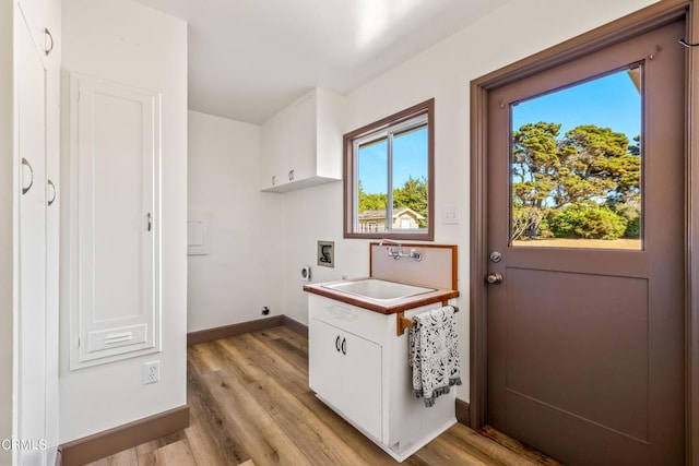 washroom with cabinets, washer hookup, electric dryer hookup, sink, and light hardwood / wood-style flooring