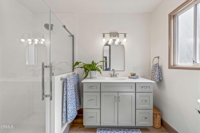 bathroom featuring a wealth of natural light, hardwood / wood-style floors, vanity, and a shower with shower door