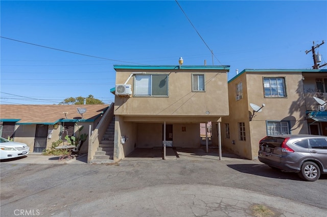 view of front of property with a carport and an AC wall unit