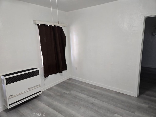 spare room with heating unit and light wood-type flooring