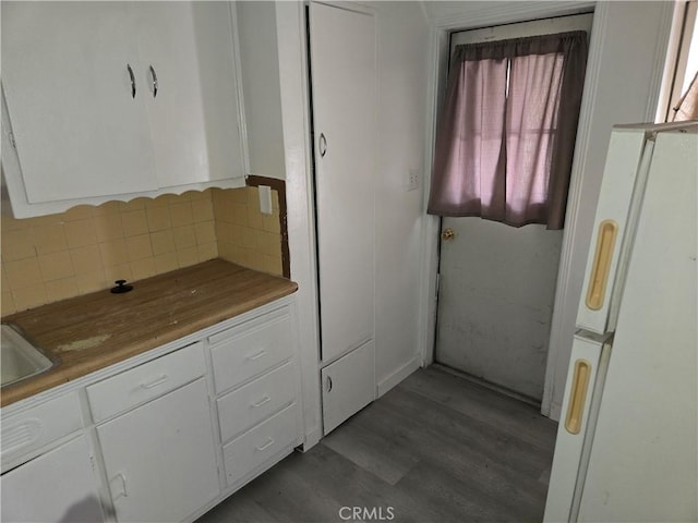 kitchen featuring white cabinets, decorative backsplash, white refrigerator, and light wood-type flooring