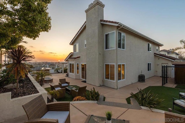 back house at dusk with central AC unit, a patio area, and outdoor lounge area