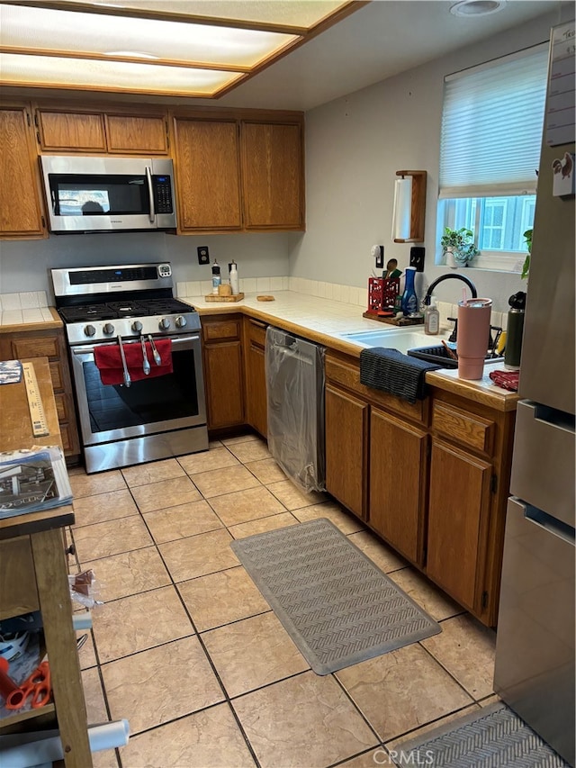 kitchen featuring tile counters, appliances with stainless steel finishes, and light tile patterned flooring