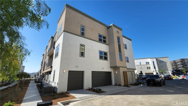 view of building exterior with a garage and central AC unit