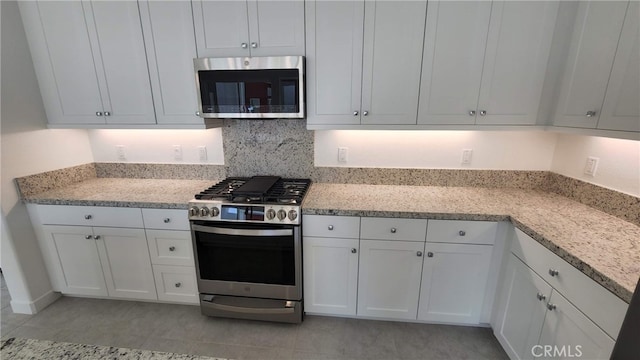 kitchen featuring decorative backsplash, white cabinets, appliances with stainless steel finishes, and light stone countertops