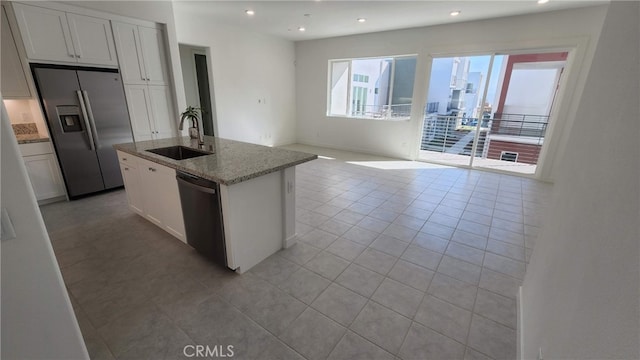 kitchen featuring light stone counters, sink, a center island with sink, white cabinetry, and appliances with stainless steel finishes