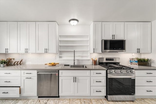 kitchen featuring appliances with stainless steel finishes, tasteful backsplash, white cabinetry, and sink