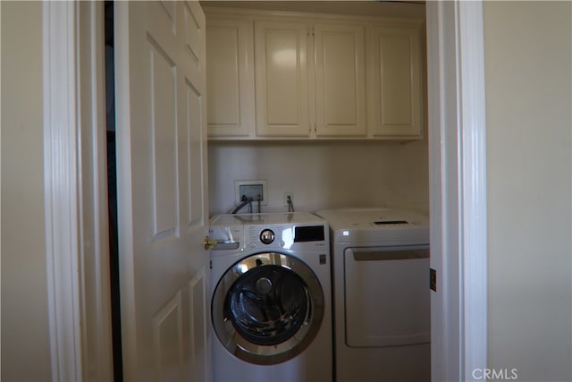 clothes washing area with cabinets and washing machine and clothes dryer