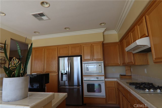 kitchen with ornamental molding, white appliances, and tile counters