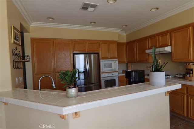 kitchen featuring sink, tile counters, white appliances, and a center island