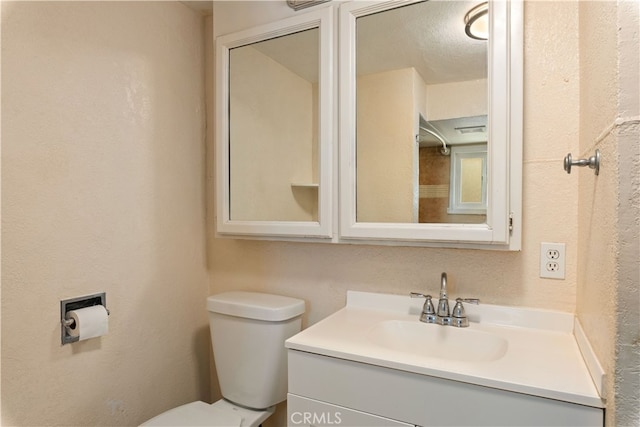 bathroom featuring a textured ceiling, vanity, and toilet