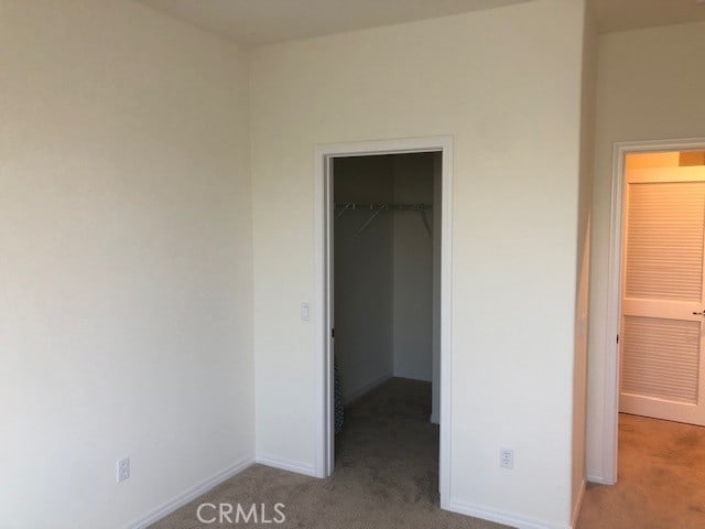 unfurnished bedroom featuring a closet, carpet, and a walk in closet