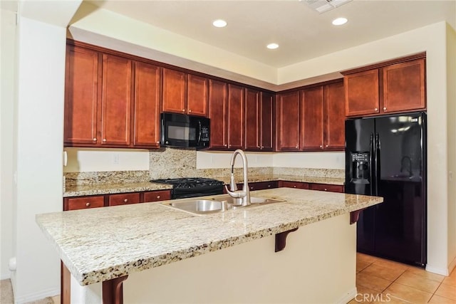 kitchen featuring light tile patterned floors, a breakfast bar area, light stone countertops, black appliances, and a sink