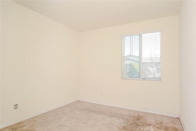 spare room with light carpet and baseboards