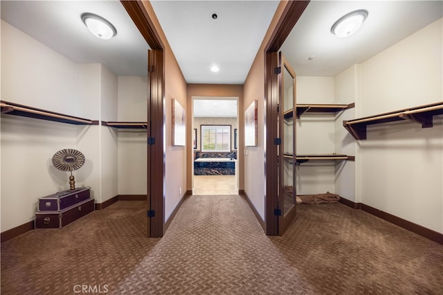 walk in closet featuring dark carpet