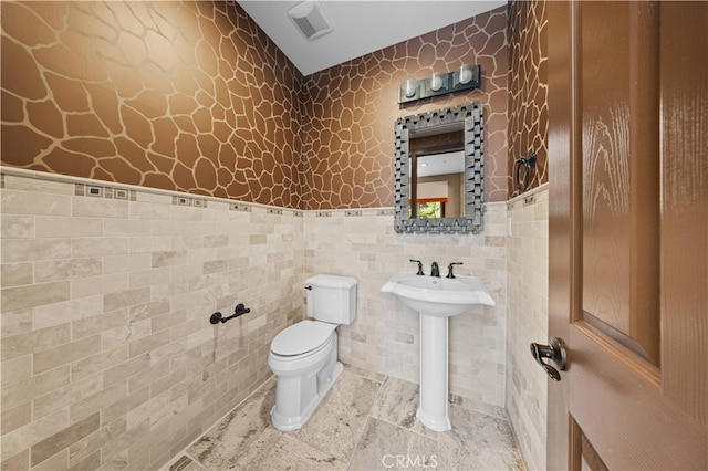 bathroom featuring sink, tile walls, and toilet