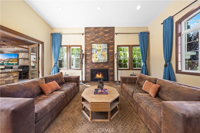 living room featuring carpet floors, a stone fireplace, and a wealth of natural light