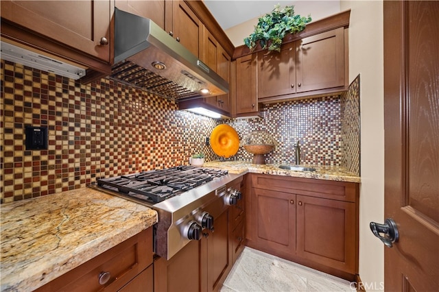 kitchen with light stone counters, sink, stainless steel gas stovetop, range hood, and decorative backsplash