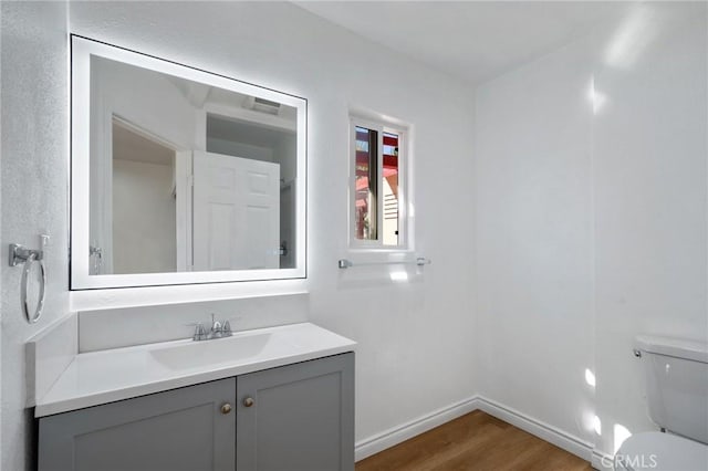 bathroom with hardwood / wood-style floors, vanity, and toilet